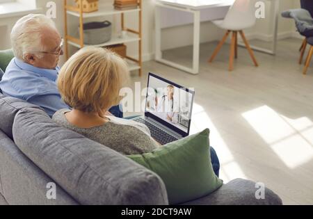 La coppia più anziana è seduta a casa nel soggiorno e parlare con il medico di famiglia tramite il collegamento video Foto Stock