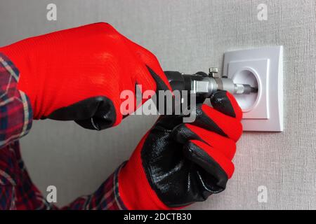 Esercitazione per installare il socket. Con le mani in guanti da lavoro rossi serrare la chiave a bussola con un cacciavite. DYI Foto Stock