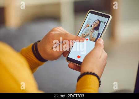 L'uomo usa uno smartphone per scorrere i profili delle donne e preme un pulsante del cuore con il dito. Foto Stock