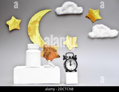 concetto di sonno sano. capsule mediche e sveglia su piedistallo bianco. melatonina e ritmi circadiani. bottiglia senza marchio con sonniferi. luna Foto Stock