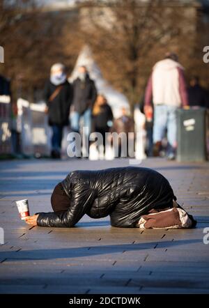 Amburgo, Germania. 23 Nov 2020. Profondamente piegata, una donna si inginocchia su un sentiero su Jungfernstieg tra i passanti e chiede denaro. Credit: Christian Charisius/dpa/Alamy Live News Foto Stock