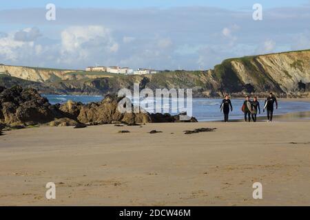 I surfisti che portano le loro tavole da surf e camminano sulla Great Western Beach a Newquay in Cornovaglia. Foto Stock