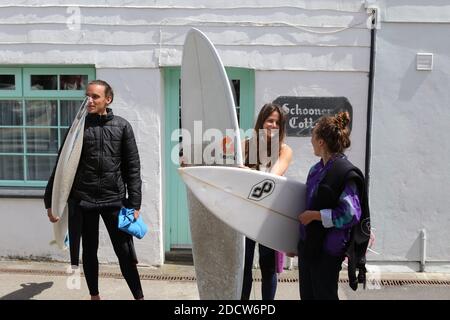 Inghilterra, Cornovaglia, Newquay, due surfisti bionde che indossano mute e tengono tavole da surf nel centro della città . Foto Stock