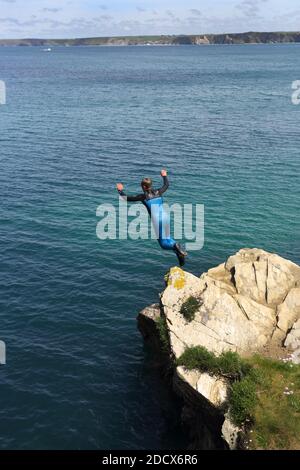 Un giovane adolescente tombstoning off scogliere su Towan promontorio in Newquay in Cornovaglia. Foto Stock