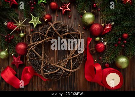 Preparandosi per fare la corona di Natale su sfondo marrone di legno. Vista dall'alto. Concetto di festa di Capodanno o di Natale Foto Stock