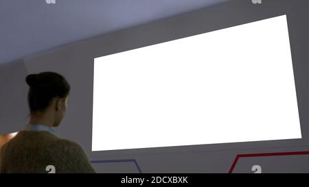 Donna che guarda la grande vuoto bianco schermo a parete - cinema mock up Foto Stock