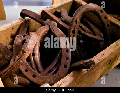 Mucchio di vecchie scarpe da cavallo arrugginite abbandonate in una scatola di legno. Foto Stock