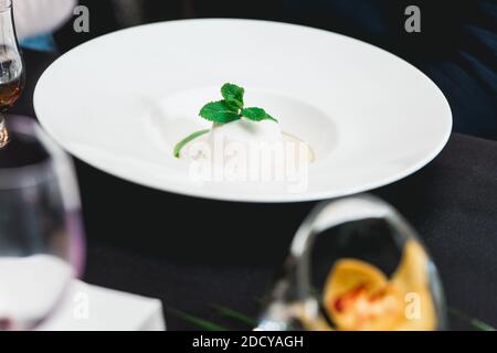 dessert al cocco con sorbetto, dessert gourmet su un piatto bianco in un ristorante. Foto Stock