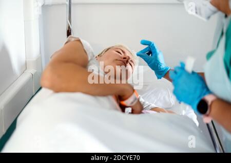 Covid 19 test fatto su una donna che si stese il letto dell'ospedale Foto Stock