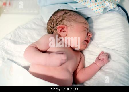 Bambino neonato in attesa di essere vestito dopo la nascita Foto Stock