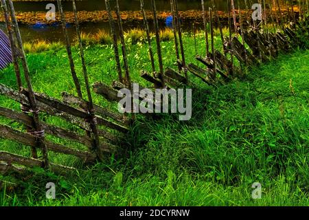 Vecchio palo di legno recinto da su prato erboso rurale. Tipico stile medievale di recinzione utilizzato in agricoltura. Foto Stock