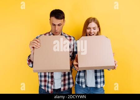 gioiosi giovani amici, con scatole di pizza su sfondo giallo Foto Stock