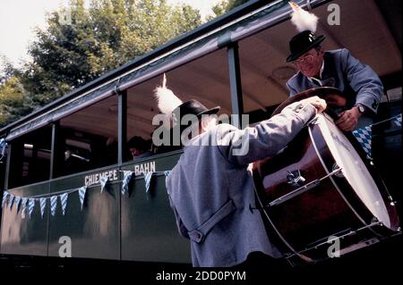 GERMANIA / Baviera / Chiemsee / uomo in abiti tradizionali che viaggiano sul treno e il suo amico sta aiutando a caricare il suo grande tamburo attraverso la finestra. Foto Stock