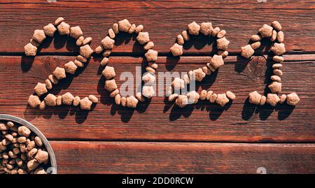 L'iscrizione 2021 è disposta con cibo secco per cani su uno sfondo di legno marrone e una ciotola di cibo per cani nell'angolo. Originale creativo Natale layo Foto Stock