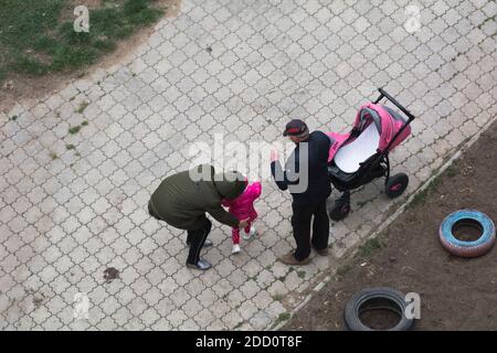 Tiraspol, Moldavia - 22 aprile 2020: Un uomo e una donna con un bambino camminano sulla strada durante la quarantena. Pandemic Covid-19 Foto Stock