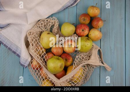 Piatto di mele biologiche in borsa eco mesh con tovagliolo di lino bianco. Vegan, senza plastica, concetto eco-compatibile Foto Stock