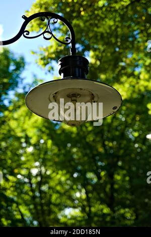 Vecchia lampada da parete bianca e nera realizzata con un disco metallico, con una cupola di vetro che protegge la lampadina. Foto Stock