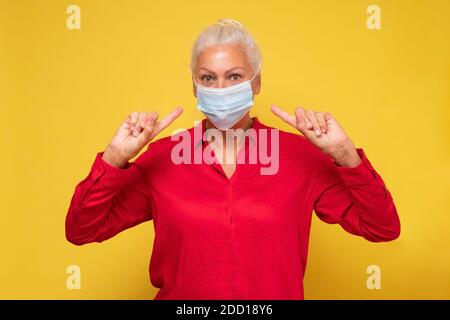 Donna anziana in una maschera medica che punta al viso. Pericoli del coronavirus per gli anziani. Foto Stock
