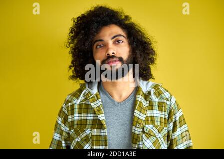 ritratto di felice uomo arabo isolato in studio, bel ragazzo in posa casual a macchina fotografica, ha capelli neri lunghi ricci, maschio calmo di aspetto indiano o arabo Foto Stock