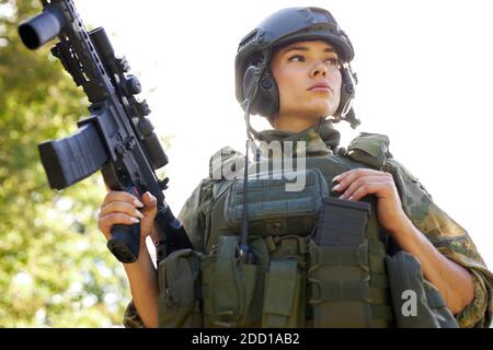 coraggiosa donna caucasica è impegnata in armi da caccia pistola o fucile, indossando tuta militare. bersaglio sparato. cacciatrice femminile in foresta selvaggia, natura. caccia di successo. caccia sport concetto Foto Stock