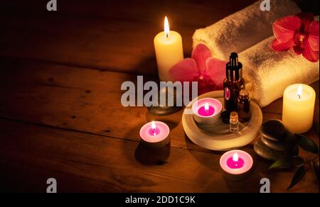 centro benessere romantico - oli essenziali con pietre e fiori da massaggio in altezza su sfondo di legno con spazio di copia Foto Stock