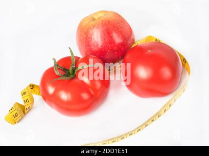 Vita morta: Due pomodori e una mela, e un centimetro accanto a loro. Mangiare sano Foto Stock