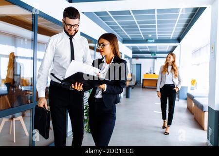 I colleghi di lavoro comunicano, discutono di documenti, camminano lungo il corridoio dell'ufficio Foto Stock