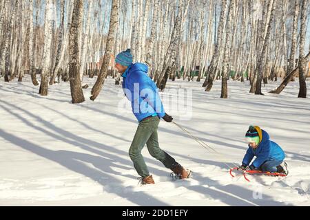 padre che ha dormito suo figlio in inverno. persone per una passeggiata all'aperto Foto Stock