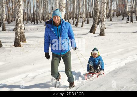 padre che ha dormito suo figlio in inverno. persone per una passeggiata all'aperto Foto Stock