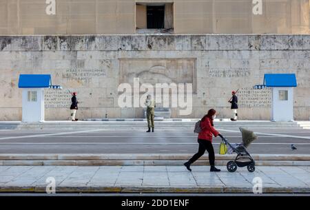 Atene Grecia, 19 novembre 2020. Donna che indossa una maschera protettiva per coronavirus con carrozzina davanti al Parlamento. Guardie e un soldato sconosciuto mon Foto Stock