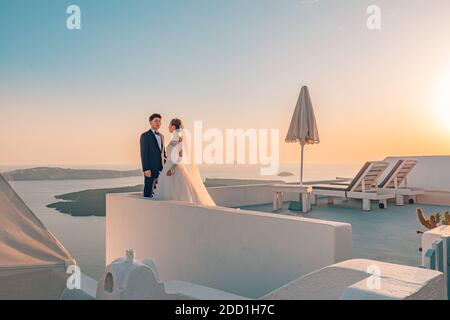 Giovane coppia luna di miele sulla più romantica isola di Santorini, Grecia. Coppia asiatica al tramonto con vista mare, romanticismo, amore, concetto di luna di miele Foto Stock