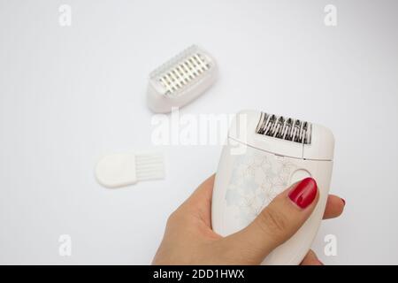 Una serie di mezzi per l'epilazione su sfondo bianco. Rimozione dei peli superflui. Epilatore moderno con una mano femminile Foto Stock