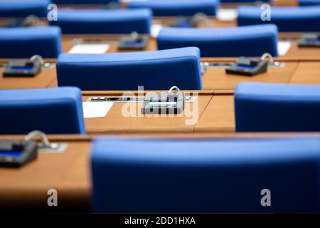 All'interno di una sala del parlamento vuota. Sedie blu in linea con le macchine di voto per ogni posto sulla scrivania. Foto Stock