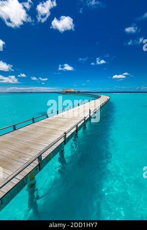 Maldive villa su pali d'acqua, viaggi estivi di lusso. Mattina luce del sole, lungo molo di legno sotto il cielo blu nuvoloso. Bungalow di lusso, mare incredibile Foto Stock