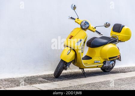 Vecchio scooter Vespa sulla strada in tradizionale strada in pietra, strada di fronte di muro bianco. Foto Stock