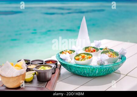 Ceviche gourmet frutti di mare su tavola bianca. Deliziose ceviche di gamberi con verdure, spezie e lime da vicino su un piatto. Lussuoso ristorante all'aperto Foto Stock