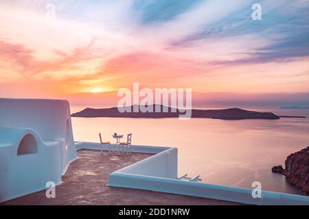 Ristorante all'aperto sotto il fantastico paesaggio del tramonto, sedie per coppie. Romantica vista del tramonto, cielo arancione e nuvole. Vacanza estiva, viaggio di nozze Foto Stock