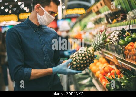 uomo con un ananas in piedi vicino al bancone con frutta Foto Stock