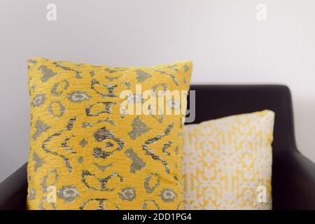 Poltrona in pelle nera con cuscini decorati in giallo e grigio e bianco Foto Stock