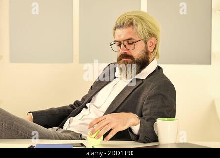 Business manager rilassante. Lavoro in ufficio. Concetto aziendale. Hipster giocare a tennis palla. Burnout e mancanza di idee. Concetto di crisi. Uomo imprenditore di successo formale abito da lavoro seduta interni ufficio. Foto Stock