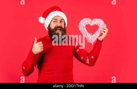 Bell'uomo amore inverno vacanze sfondo rosso. buon natale e Felice Anno Nuovo. Il ragazzo indossa il cappello di Santa. Innamorati. Ti voglio bene. Lasciatemi sciogliere il vostro cuore. Benvenuti Natale nel vostro cuore. Foto Stock