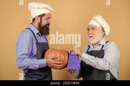 Concetto di mangiare. Dinastia culinaria. Insegnamento culinario. Libro culinario. Cuochi professionali del ristorante degli uomini bearded maturi. Deliziosa ricetta. Il team della cucina prepara il cibo. Tradizione familiare. Chef uomini cucina. Foto Stock