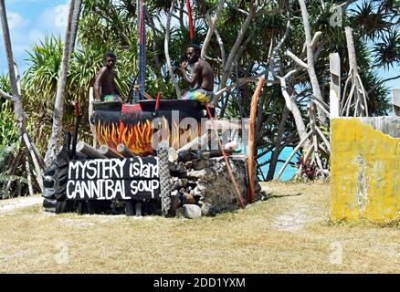 La gente del posto posa per le immagini in un enorme vaso nero con le fiamme dipinte per la zuppa di cannibale su Mystery Island, una fermata popolare di crociera a Vanuatu, nel Pacifico del Sud. Foto Stock