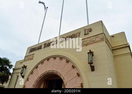 L'edificio Art Deco National Tobacco Company a Napier, Isola del Nord, Nuova Zelanda. Rose decorative sull'ingresso dell'arco e pali della bandiera sopra. Foto Stock