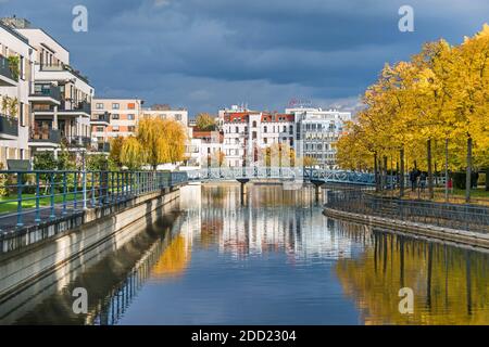 Berlino, Germania - 24 ottobre 2020: Bacino portuale Tegeler Hafen con edifici antichi e moderni, unità residenziali, ponte pedonale e albero autunnale Foto Stock