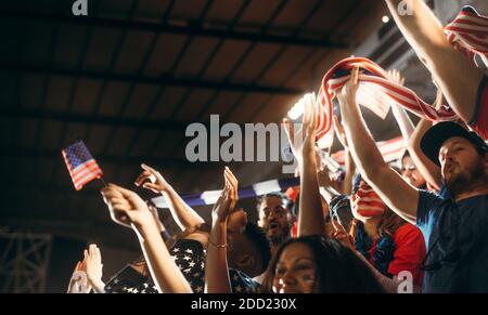 Tifosi di calcio che si acclamano con le bandiere USA durante una partita. Gruppo di tifosi di calcio che si sono godendo di un grande tempo allo stadio. Foto Stock