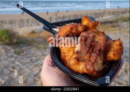 Pesce di strada olandese, filetto di merluzzo fritto con salsa all'aglio chiamato in Olanda kibbeling e mare del Nord spiaggia sullo sfondo in inverno Foto Stock