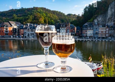 Bere birra abbaziale belga scura e forte con formaggi in giornata di sole con bella vista sul fiume Maas e città Dinant, Belgio Foto Stock