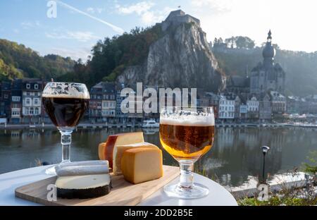 Bere birra abbaziale belga scura e forte con formaggi in giornata di sole con bella vista sul fiume Maas e città Dinant, Belgio Foto Stock