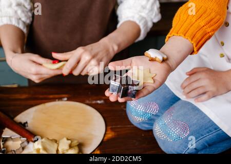 La mano della bambina che fa i biscotti tradizionali di Natale. Preparare gli uomini di pan di zenzero di Natale. Fasi di preparazione dei biscotti. Vista dall'alto. Foto Stock